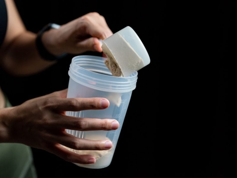 close-up-women-with-measuring-scoop-whey-protein-shaker-bottle-preparing-protein-shake